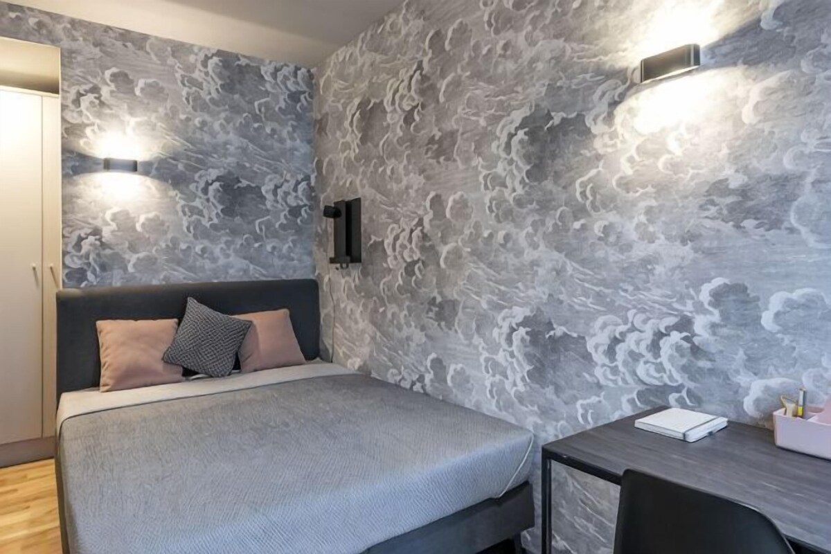 Een slaapkamer met een bed, nachtkastje en een bureau met stoel.