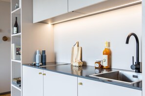 Une cuisine moderne avec un évier en acier inoxydable, une bouteille de vin et un pot de miel posés sur le plan de travail.