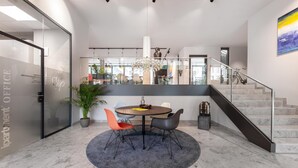 Un espacio de oficina moderno con una mesa redonda, sillas, una escalera y una pared de vidrio.