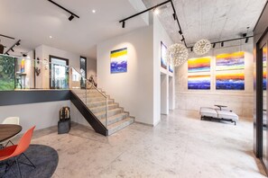 Un intérieur moderne avec un escalier, un coin repas et des œuvres d’art accrochées aux murs.