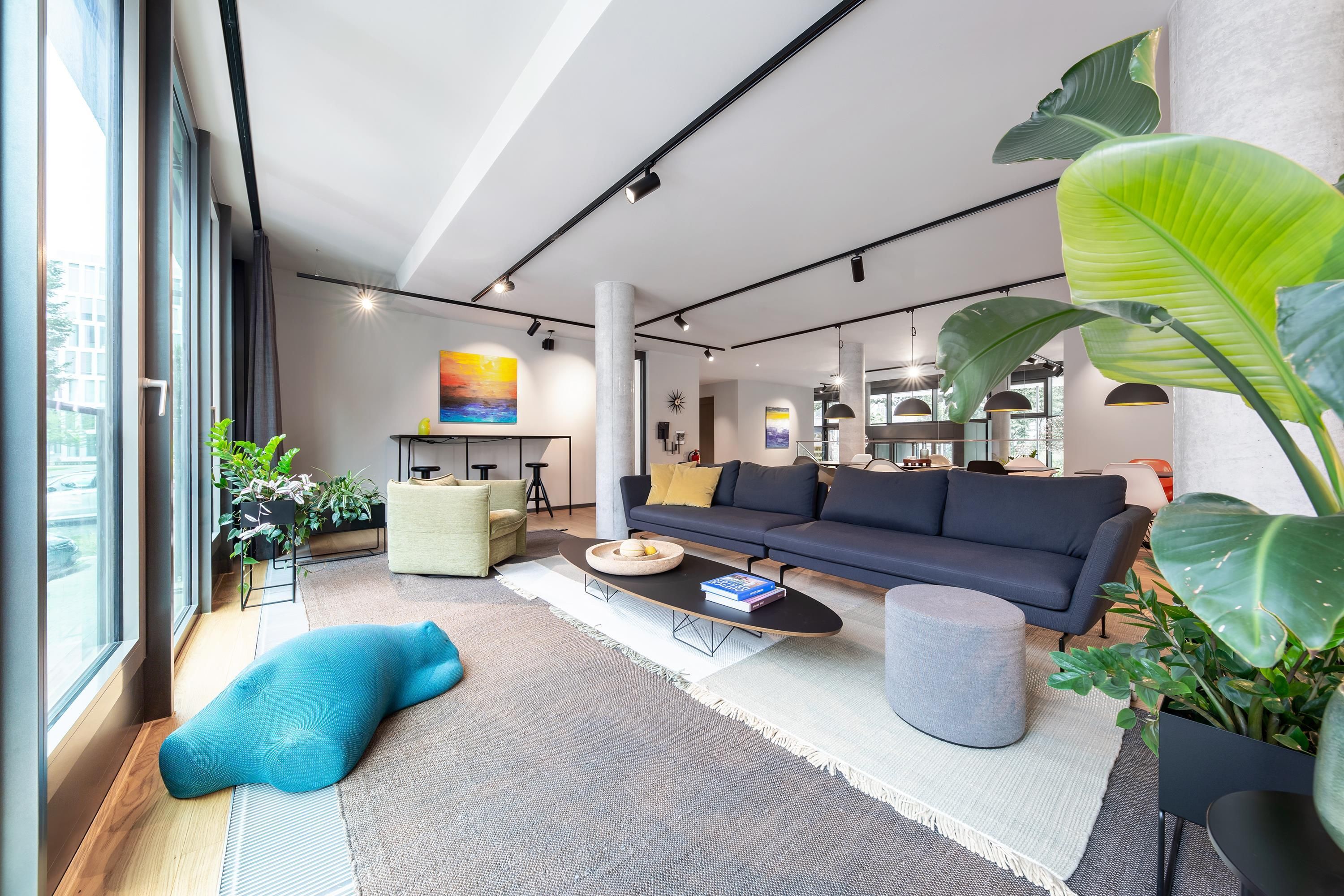 A modern living room with a sofa, coffee table, and large windows.