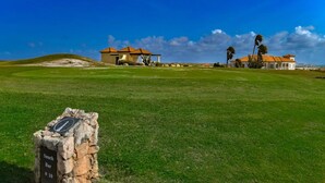 A golf course with a clubhouse, a snack bar, and a clear blue sky. - Caribbean Oasis - 3 spacious suites, private pool (Noord)