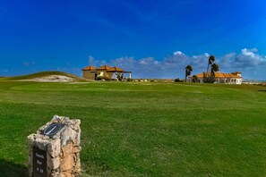 En golfbana med ett klubbhus, ett café och en klar, blå himmel.