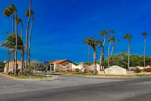 A residential area with palm trees, a road, and a sign indicating a community center.