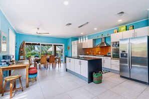 A modern kitchen with a central island, white cabinets, stainless steel appliances, and a blue accent wall.