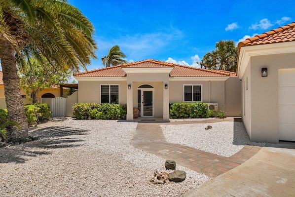 A residential property with a tiled roof, a central entrance, and a gravel driveway.
