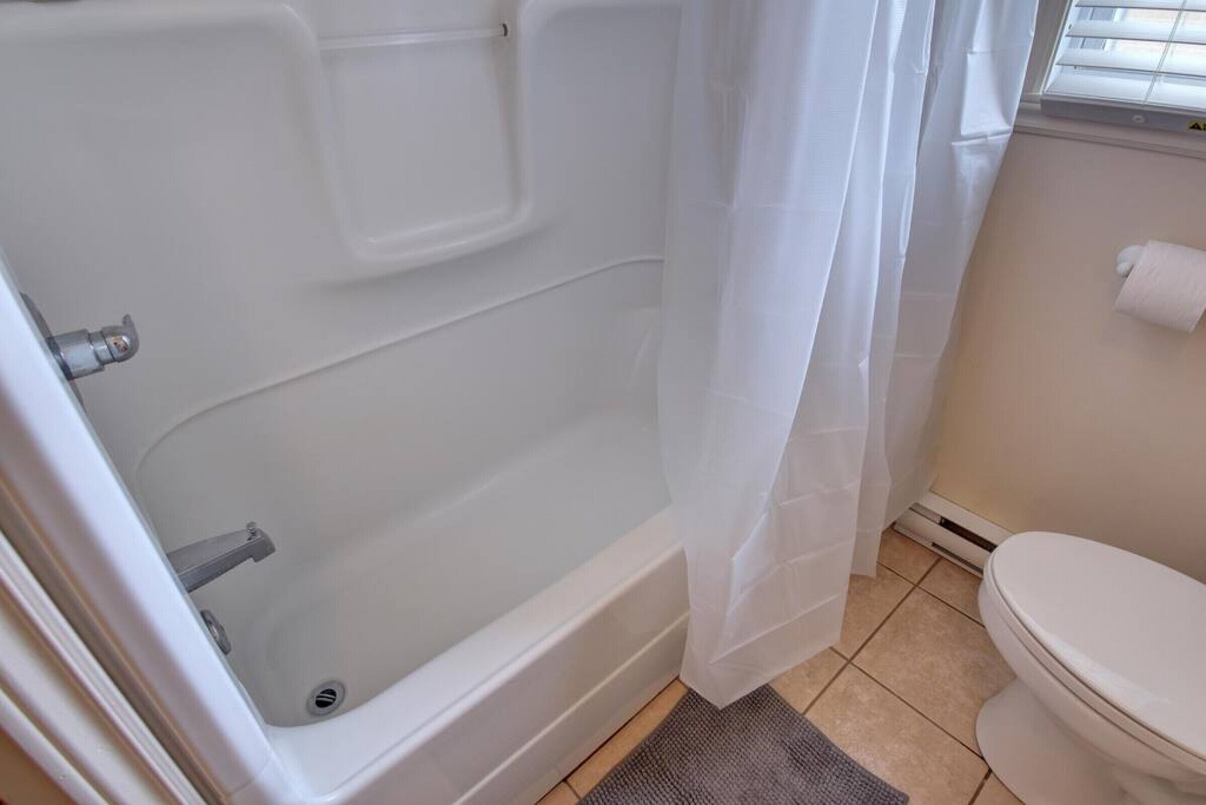 Een badkamer met een badkuip, toilet en een douchegordijn.