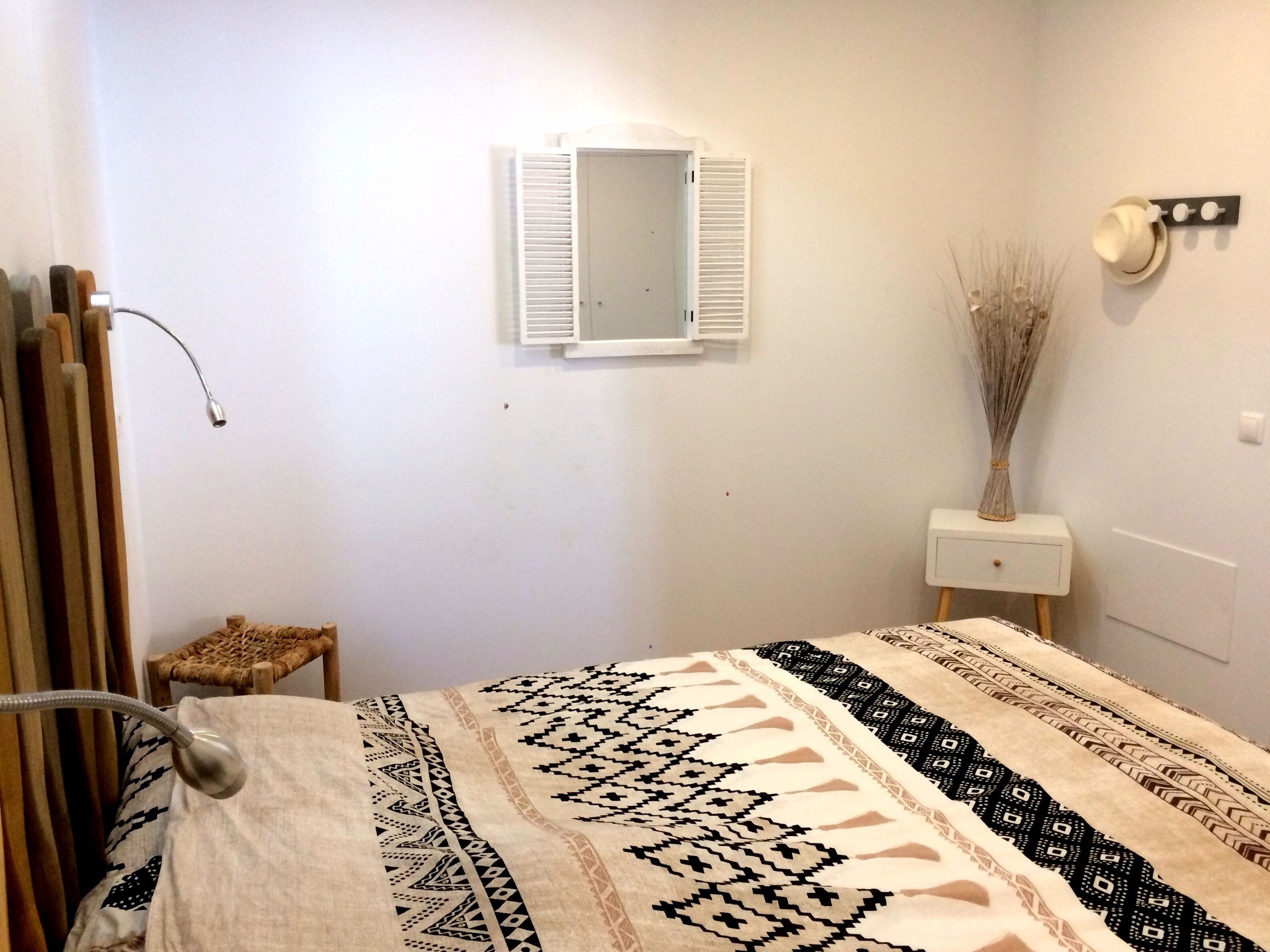 Un dormitorio con cama, mesita de noche, espejo y radiador.