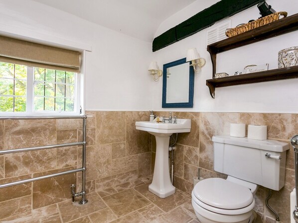 Une salle de bain avec des toilettes, un lavabo et une fenêtre.
