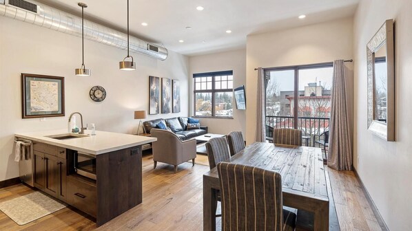 Enjoy a spacious kitchen with a central island, sink, and storage, adjacent to a living and dining area with a sofa and dining table.