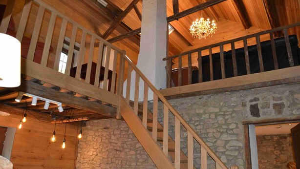 Una escalera de madera con un muro de piedra a un lado y una barandilla de madera al otro.