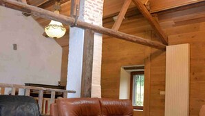 Un interior rústico de madera con un techo alto, sofás de cuero, una mesa de centro de madera y una araña.
