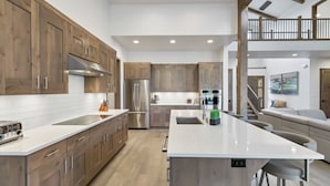 A modern kitchen with wooden cabinets, stainless steel appliances, and a large island. - Deschutes Executive Retreat - 6BR Luxury Rental (Deschutes County)
