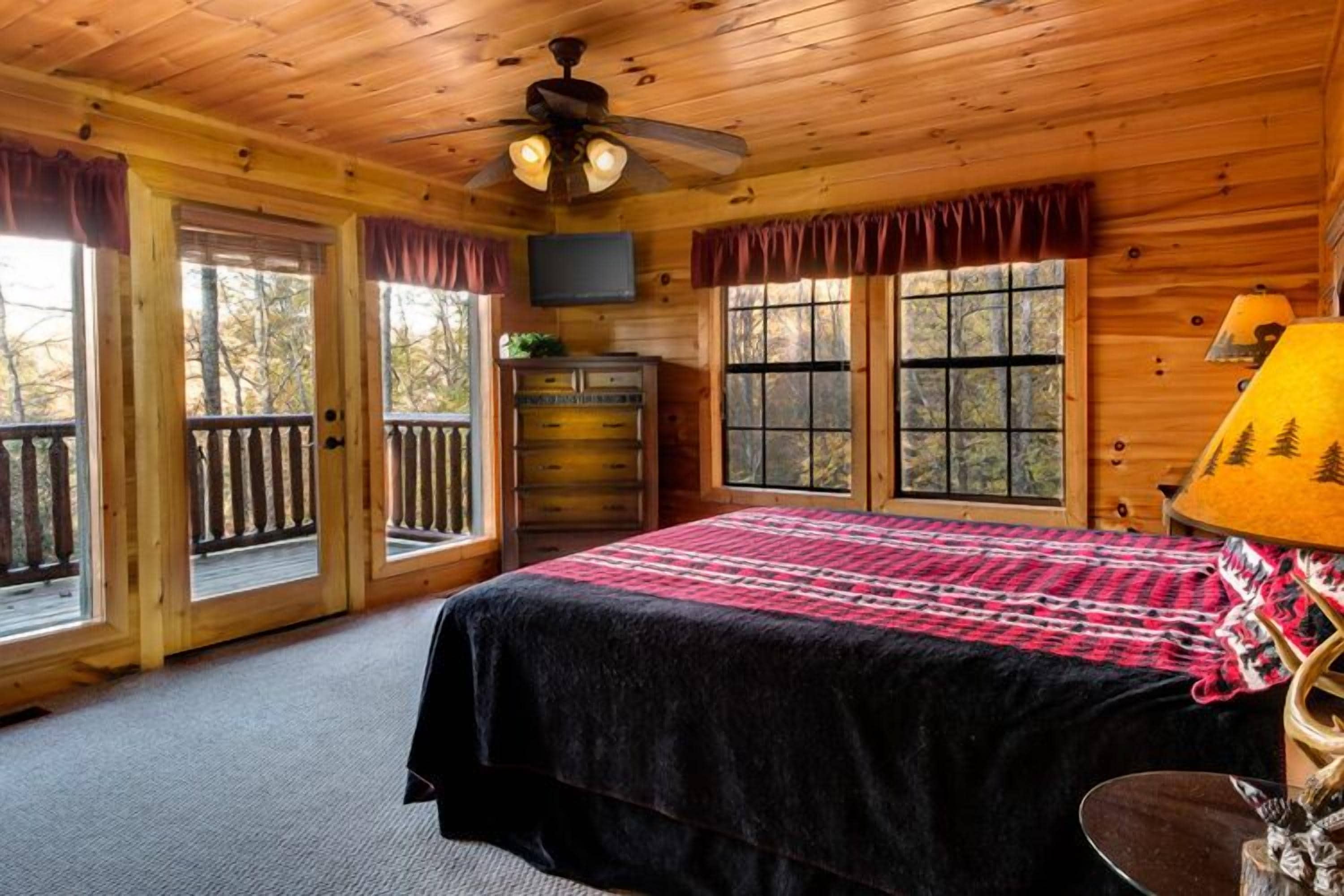 Une chambre dans une cabane en bois, avec un lit, une commode et des fenêtres.