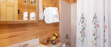 Un baño de cabaña de madera con un espejo grande, un lavabo, un inodoro y una ducha.