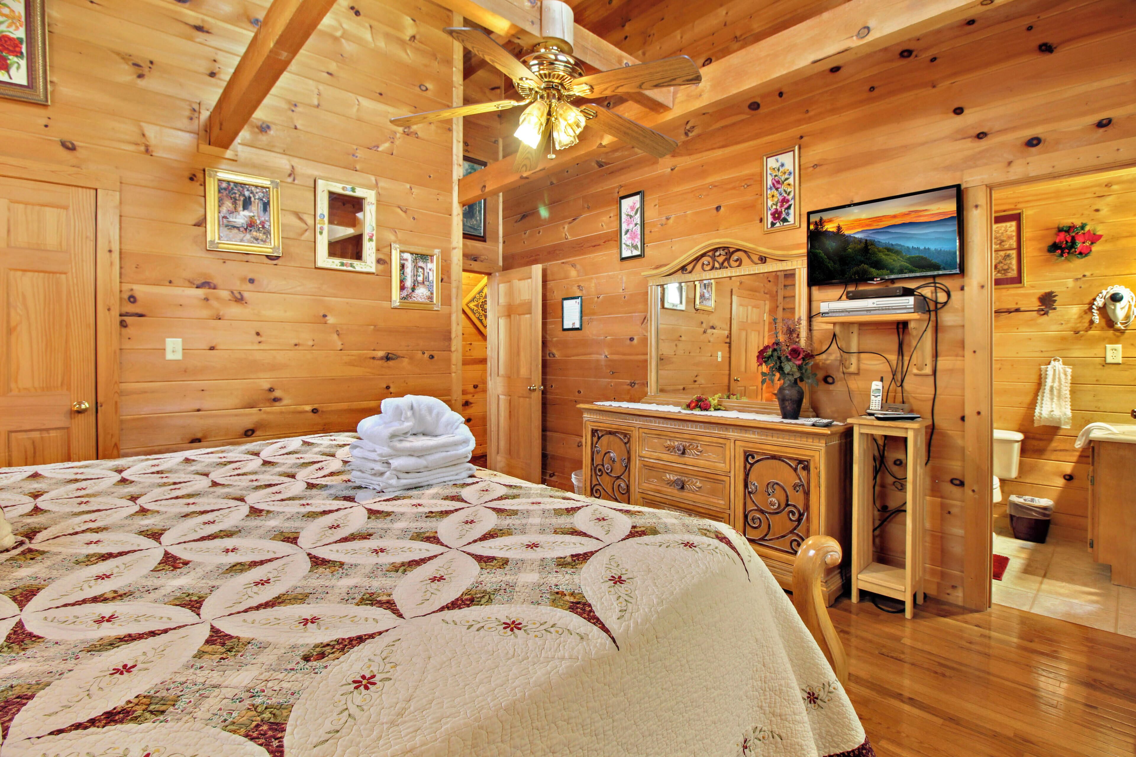 Una camera in legno con un letto, una cassettiera, una toeletta e un televisore.