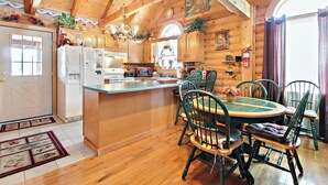 A wooden cabin interior with a kitchen, dining area, and a large window. - Alpine Ski Lodge by Jackson Mountain Rentals (Gatlinburg)