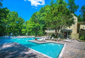A swimming pool with lounge chairs and a building in the background.