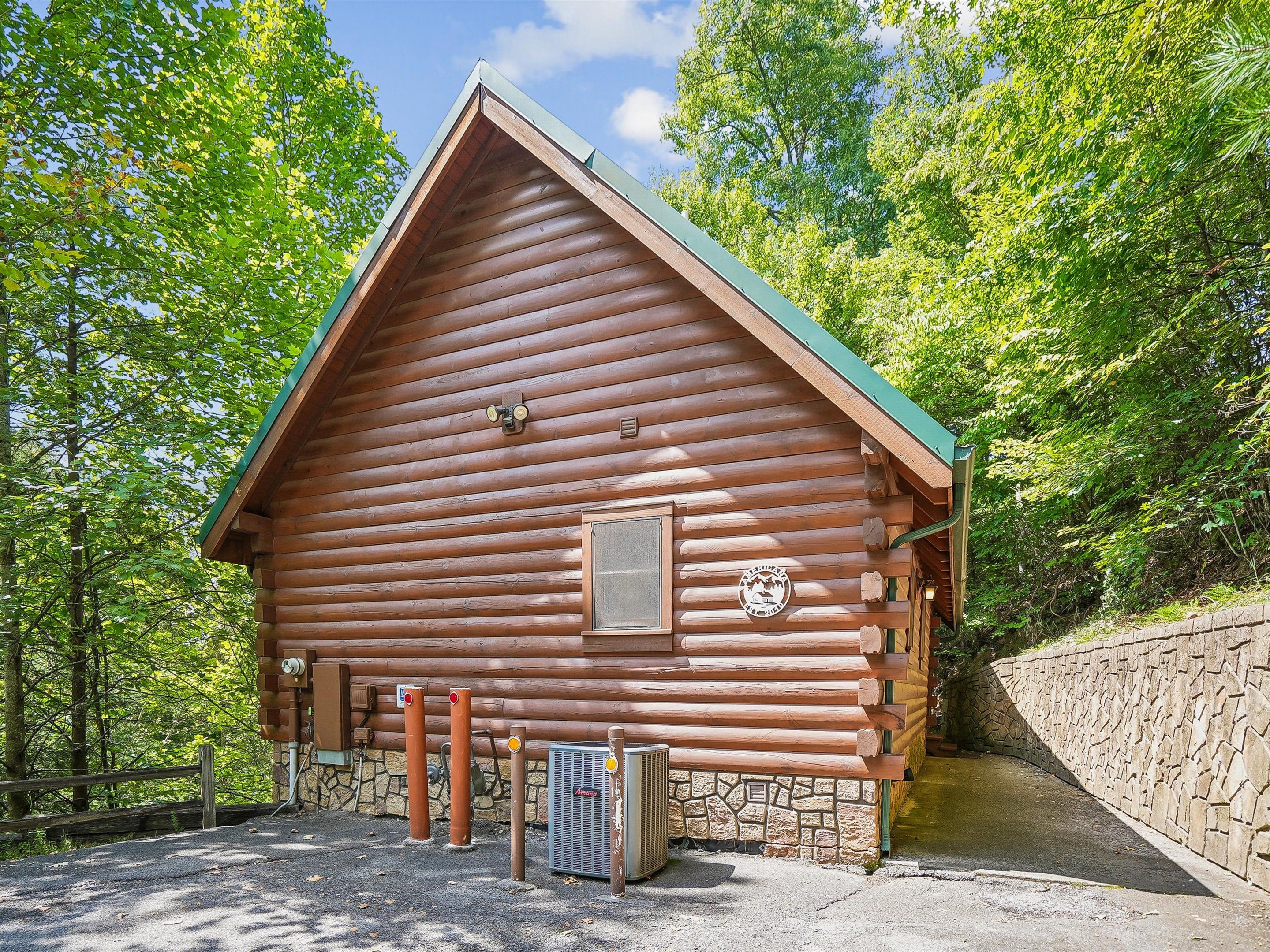A log cabin with a stone foundation, a pitched roof, and a small window with a logo.