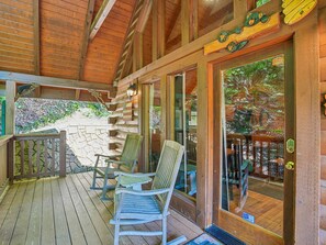 A wooden deck with outdoor seating and a stone wall. - Americana by Jackson Mountain Rentals (Gatlinburg)