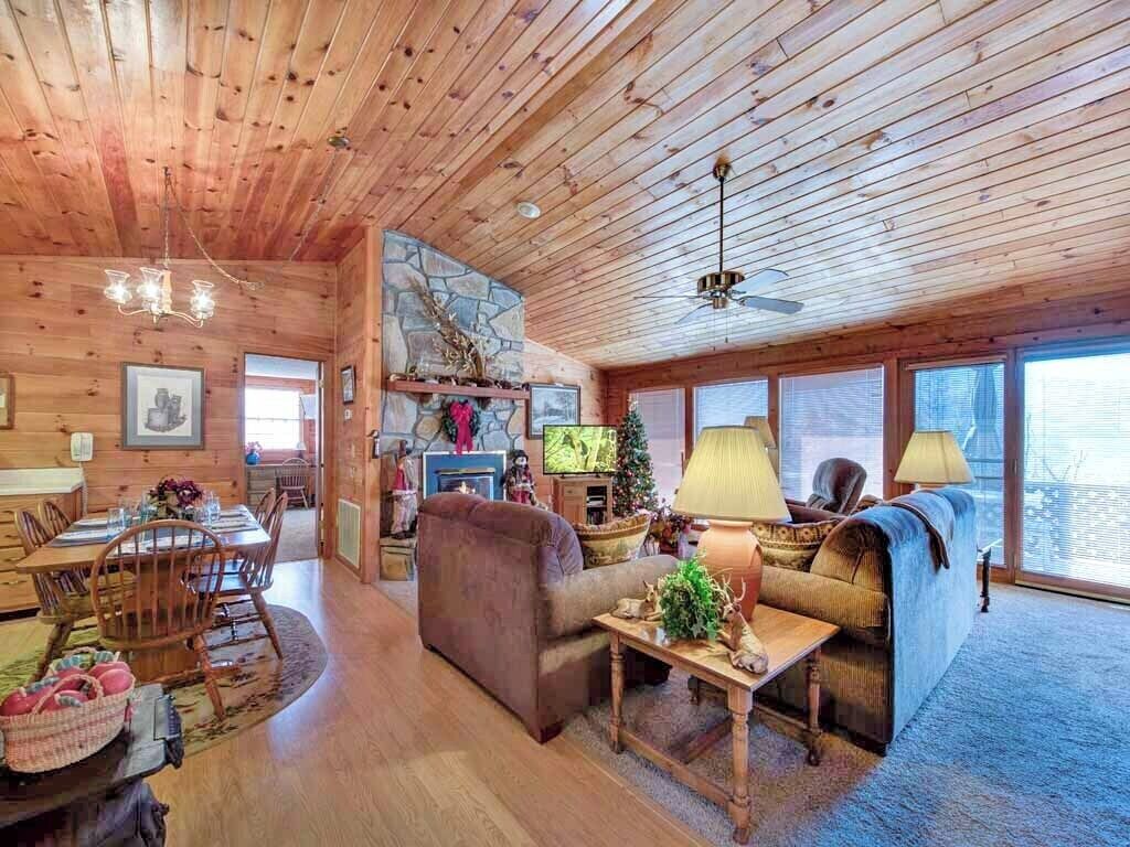 A cozy cabin interior with a dining area, a fireplace, and a large window.