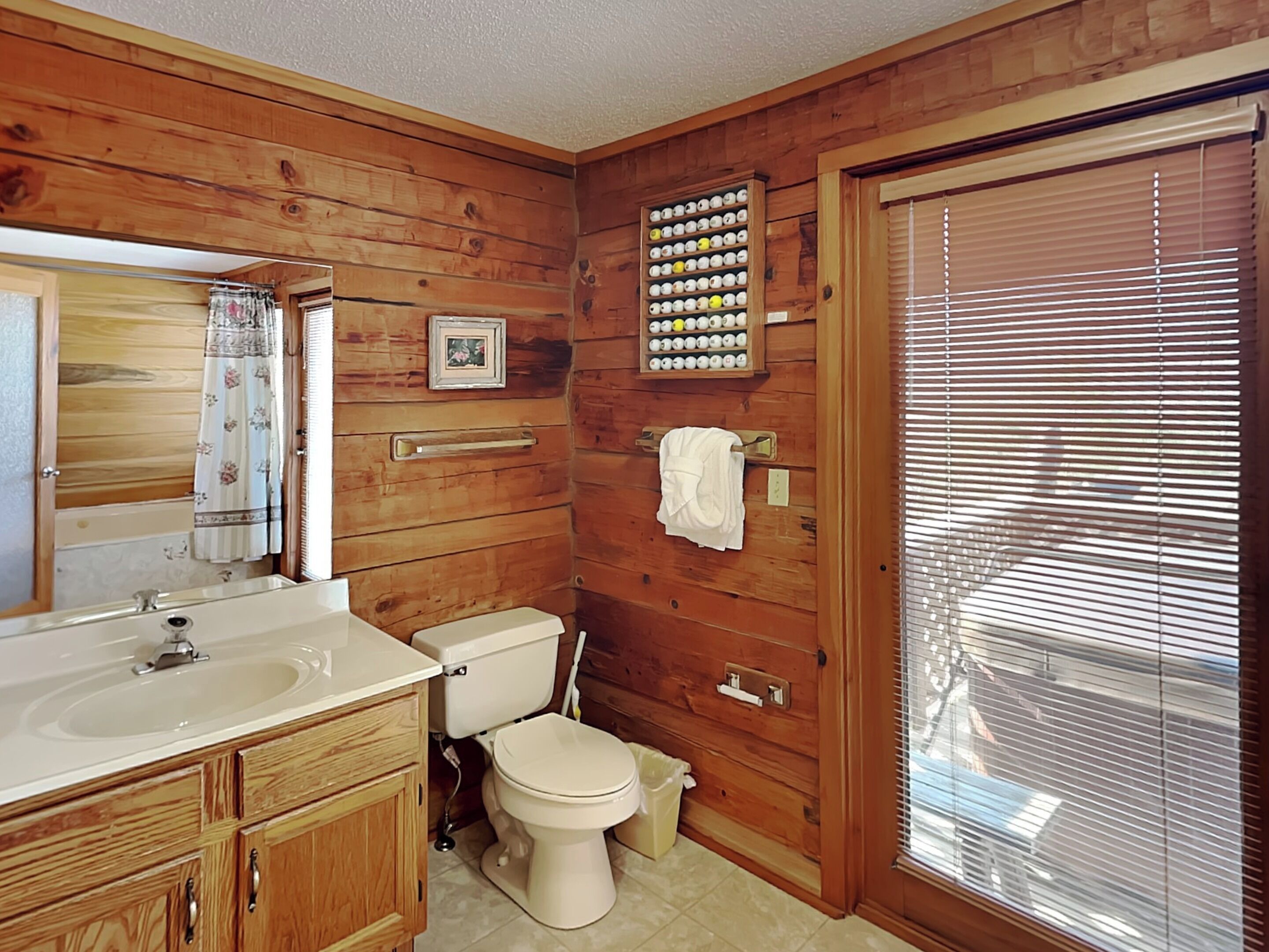 A wooden-paneled bathroom with a sink, toilet, and a towel rack.