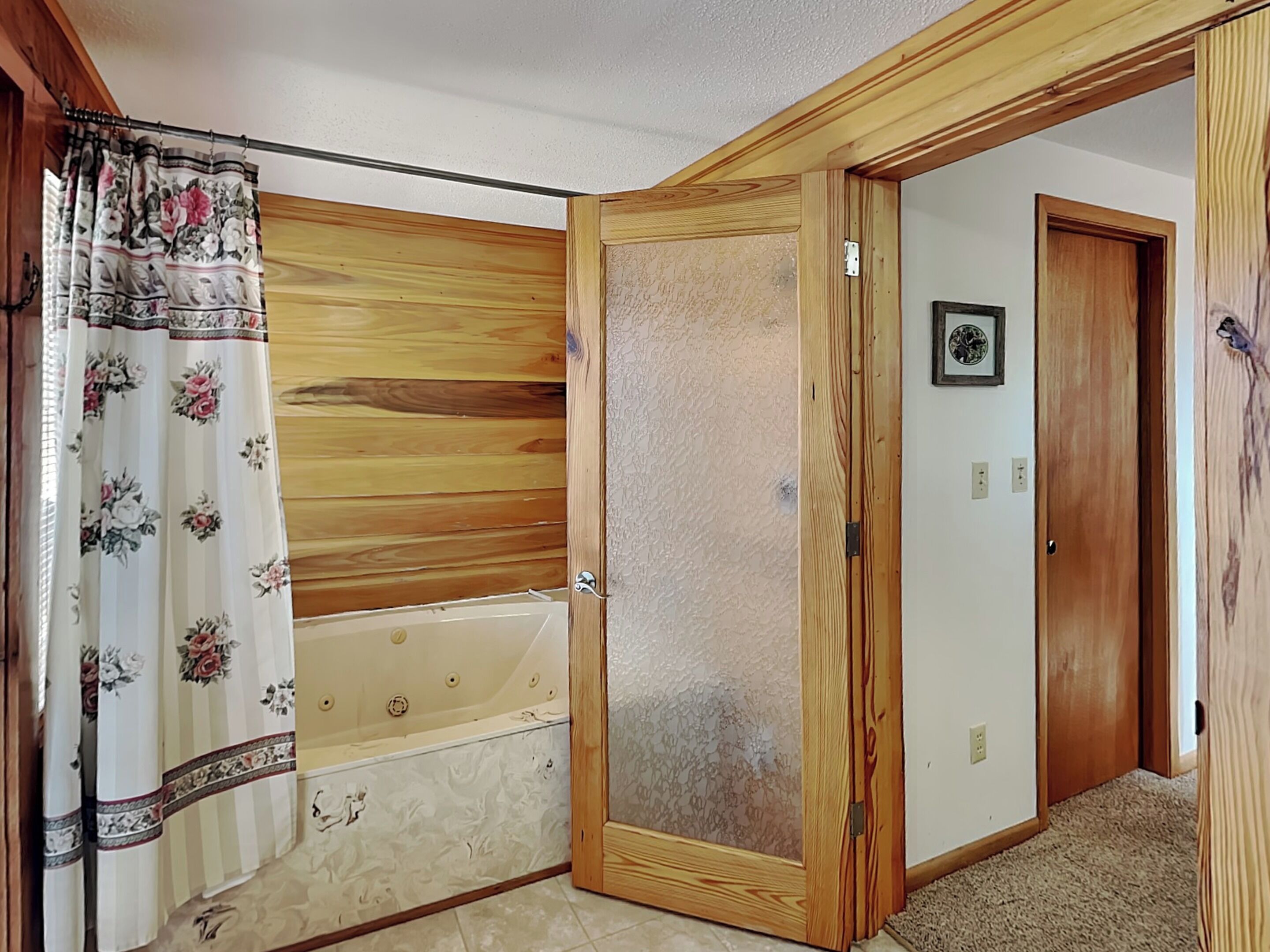 A bathroom with a wooden vanity, a bathtub, and a shower curtain.