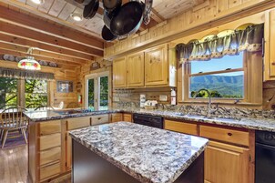 Una cocina con armarios de madera, encimeras de granito y una ventana con vistas a la montaña.