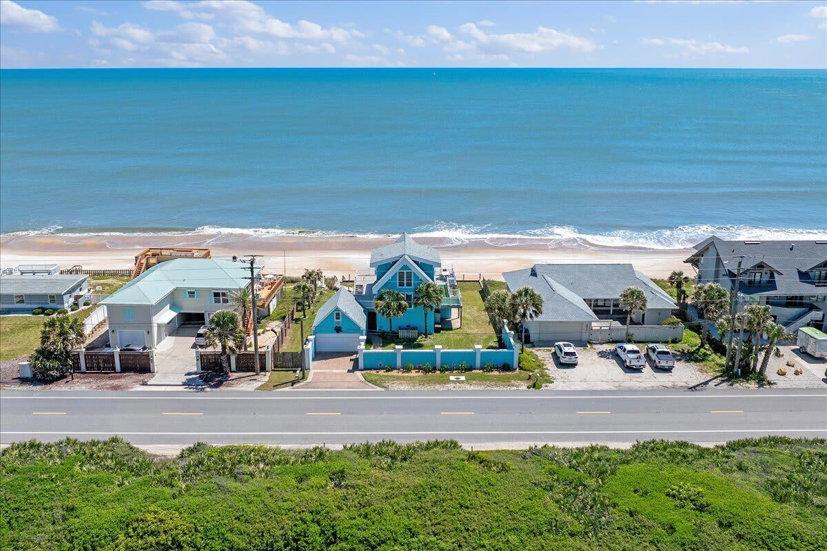 A coastal residential area with houses, a beach, and a clear sky.