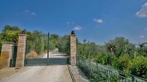 A gated entrance with a metal gate and brick pillars, surrounded by greenery and a clear sky. - Villa Flavia - Private villa, 8 bedrooms, pool, A/C, wifi, pets, Marche (Filottrano)