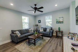 Un salon comprenant un ensemble de canapés, une table basse, un ventilateur de plafond et une bibliothèque.