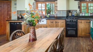 A rustic kitchen with wooden cabinets, a central island, a stove, and a dining table with chairs.