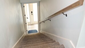 Una escalera alfombrada con barandilla que conduce a una puerta con vistas a una habitación.