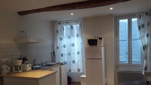 Una cocina compacta con microondas, cafetera y lavabo.