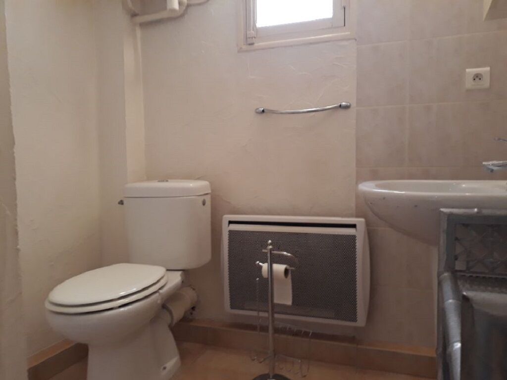 A bathroom with a toilet, a radiator, and a sink.