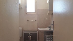 Un baño pequeño con inodoro, lavamanos y ventana.