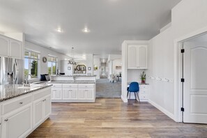 A spacious kitchen with white cabinetry, a granite countertop, and a central island.