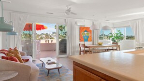 Quarto de hotel moderno com varanda, área de refeições e uma grande janela com vista.