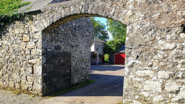 Un arco de piedra que da acceso a un edificio con una puerta roja.