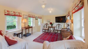 Una habitación acogedora con un tapete rojo estampado, una mesa de madera con sillas y un televisor instalado en la pared.