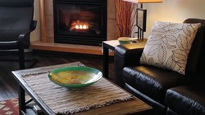 Un salon avec une cheminée, un canapé, une table basse et une lampe.