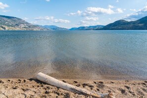 A clear lake with a sandy beach and a driftwood log.