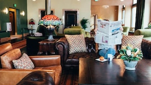 A cozy lobby with leather sofas, a coffee table, and a lamp. - Belvada Hotel (Tonopah)