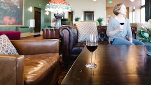 A cozy interior with leather seating, a wooden table with a wine glass, and a colorful lamp. - Belvada Hotel (Tonopah)