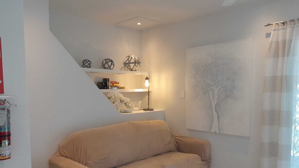A living room with a beige sofa, a round coffee table, and a painting of a tree on the wall.