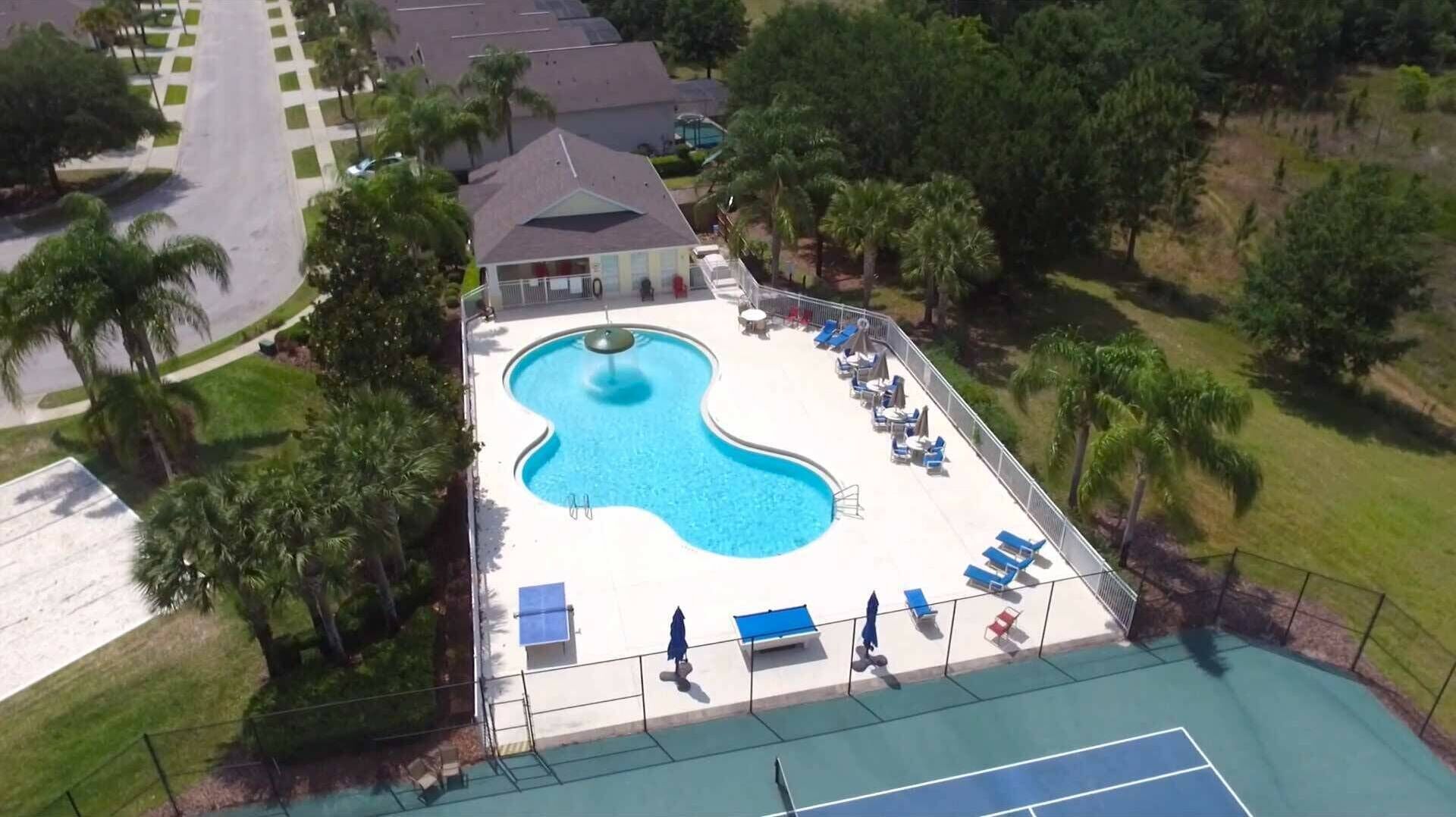 Vista aérea de un resort con piscina, sillas de descanso y palmeras.