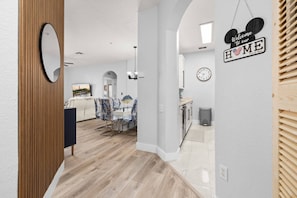 A modern interior with a dining area, kitchen, and a 'Welcome to our HOME' sign. - Windsor Hills Dream - 3BR - 2 miles from Disney! (Kissimmee)