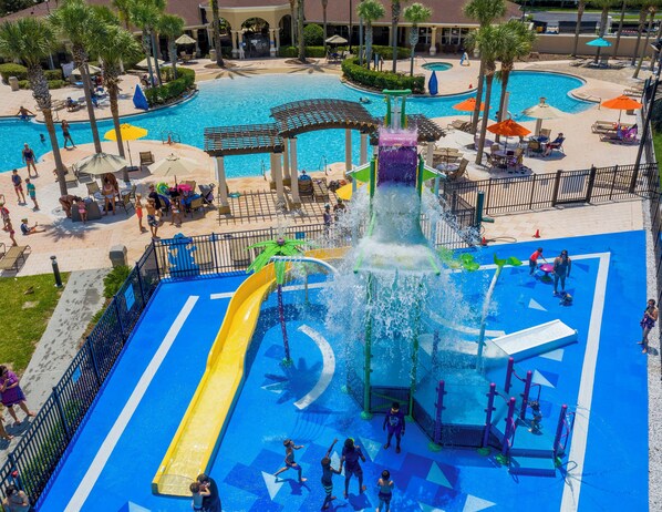 A water park with a central water slide, multiple pools, and lounge areas with umbrellas. - Windsor Hills Dream - 3BR - 2 miles from Disney! (Kissimmee)