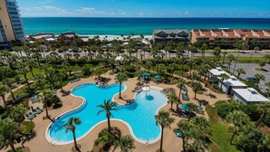 Un complexe hôtelier doté d’une grande piscine, de palmiers et offrant une vue sur l’océan.