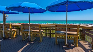 A wooden deck with blue umbrellas and wooden benches overlooking a beach. - Sea Breeze, Destin Studio, Pools, Beach (Destin)